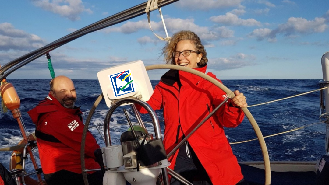 Título PER: Chica sonriente con chaqueta de agua roja gobierna desde el timón la embarcación de Avante