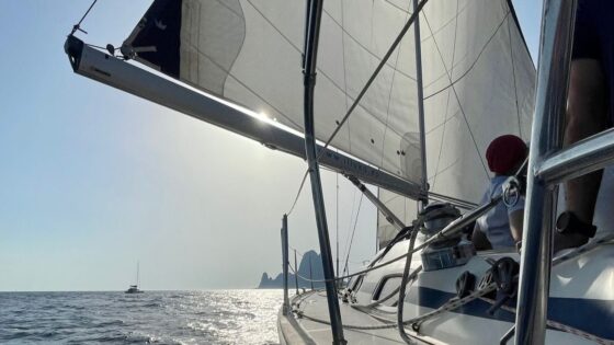 Escuela náutica de Avante: A bordo viendo vela muy abierta y el peñon Es Vedrá al fondo - Titulo Patrón de Yate - Títulos náuticos