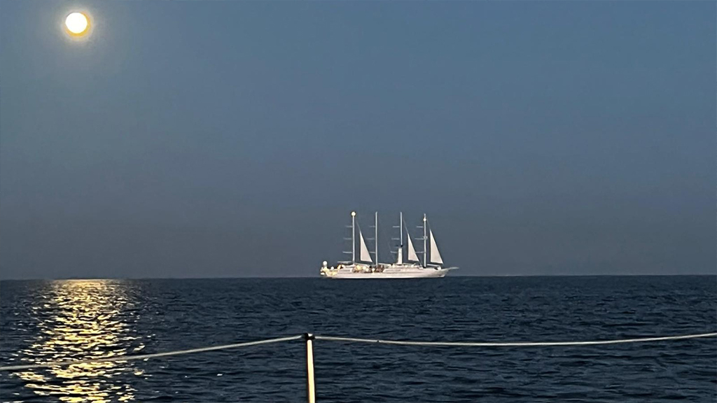 Velero de fondo en el mar oscuro con la luna iluminando