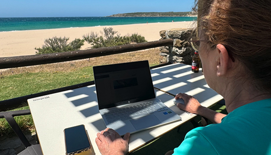 Mujer trabajando con su portátil con vistas a la playa