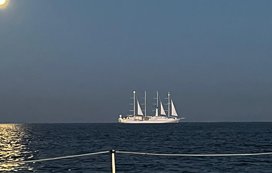 Velero navega en el océano con la luna llena