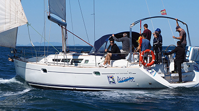 Un grupo de personas en un velero en el océano durante las prácticas de ampliación PER y vela en el crucero-escuela a Baleares, Atlantis Cinco, Valencia Mar.