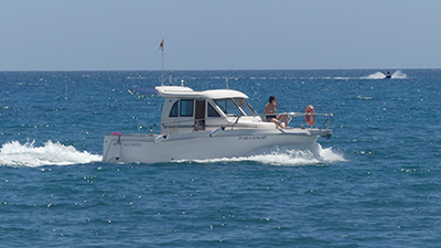 Barco navegando en aguas tranquilas con mujer tomando el sol en la proa