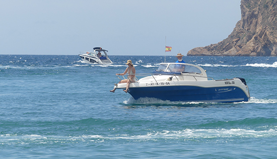 Una pareja en un yate en el mar con una montaña al fondo