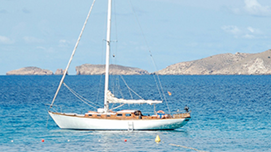 Velero en aguas tranquilas con montañas de fondo