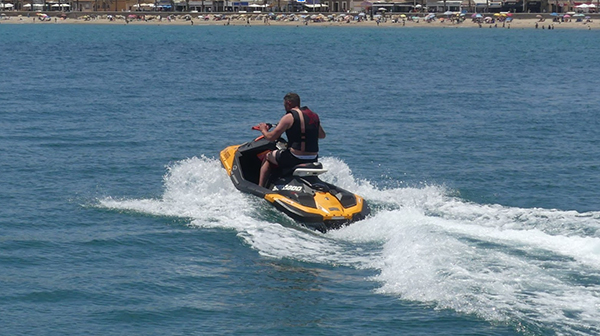 Chico disfrutando de un paseo en moto acuática en el mar.