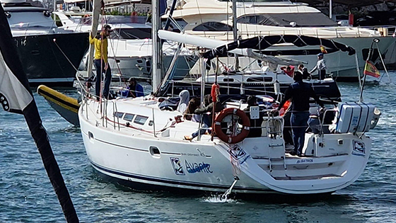 Prácticas de perfeccionamiento: El velero Albatros II de 14 metros de largo levanta la proa al paso de la ola con tripulantes llevando el barco. Curso de vela en Valencia