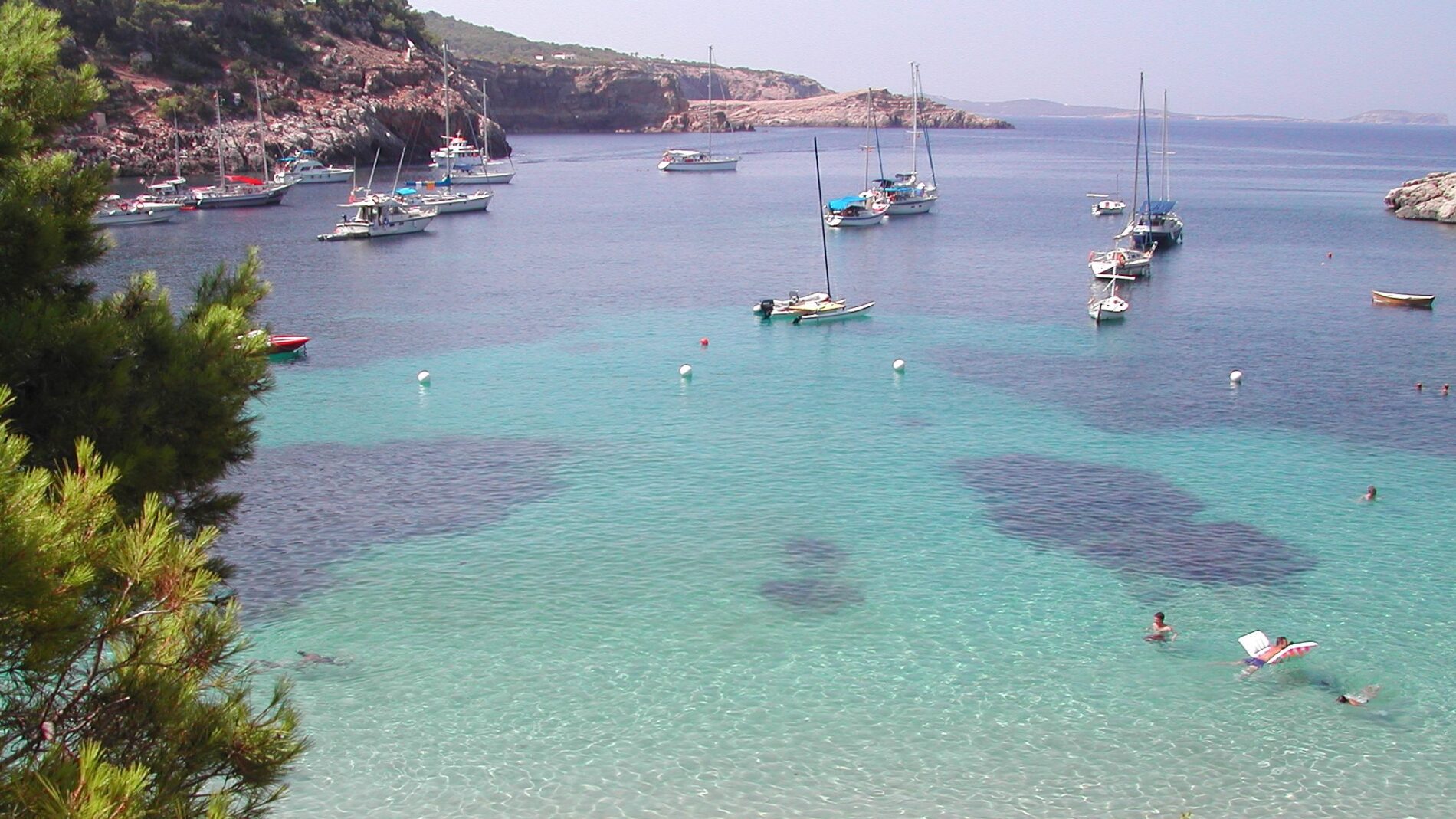 barcos fondeados en una cala de aguas transparentes